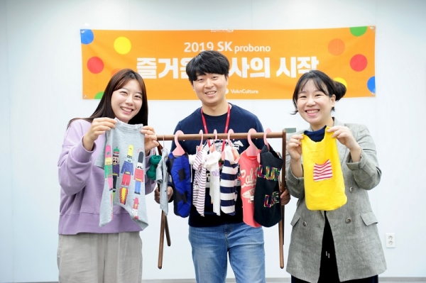 SK건설 임직원들이 직접 만든 반려동물용 겨울옷을 들고 기념촬영을 하고 있다.(사진제공=SK건설)